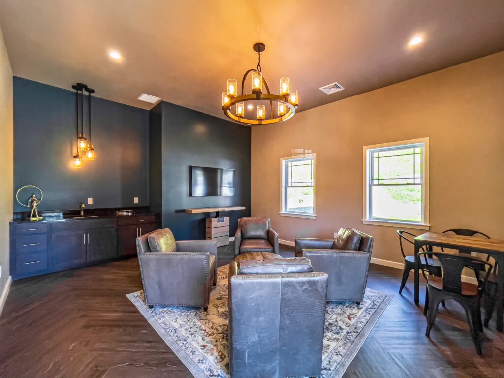 Clubroom with leather chairs, bookshelf and card table with chairs and blue accent wall